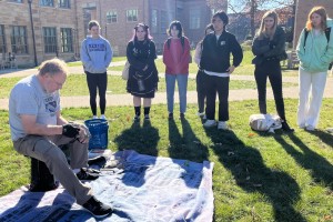 Bruce Hardy demonstrates flintknapping to students in the fall.