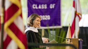 Samie Kim Falvey speaks on stage in front of Class of 2020 banner. 